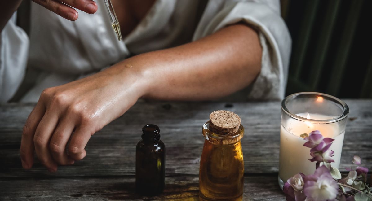 Woman treating herself holistically by applying oil onto the skin of her wrist