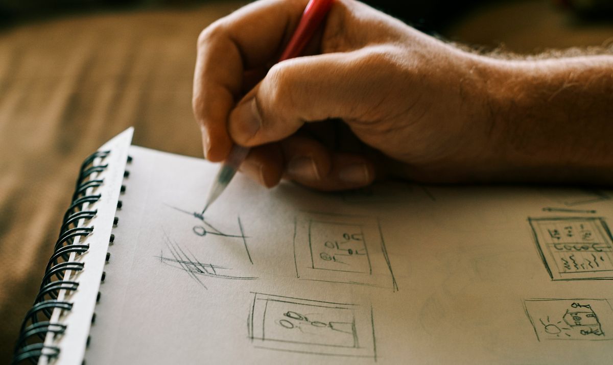 Hand hänlt einen Bleistift und zeichnet kleine Skizzen auf einen Block